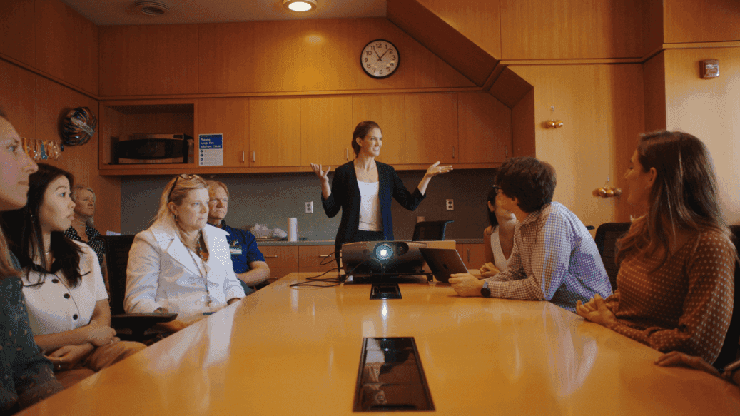 Woman speaking to people around a table
