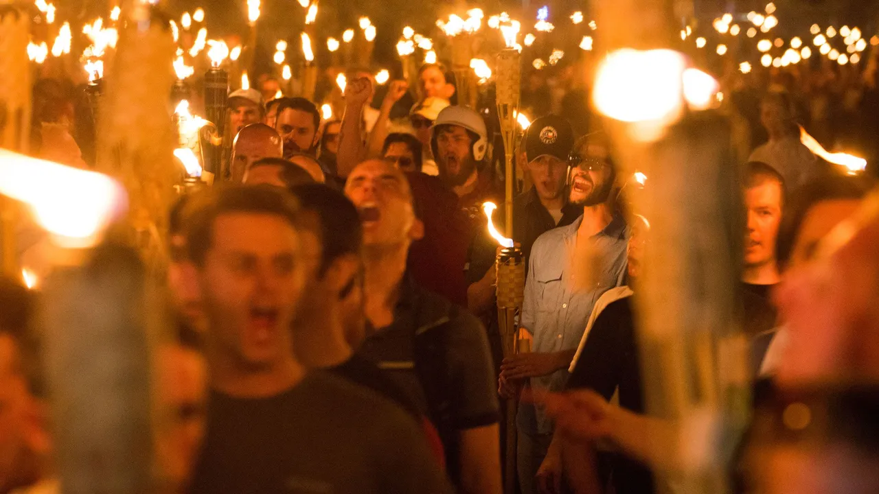 Photo of dozens of people carrying burning torches at White supremacy rally