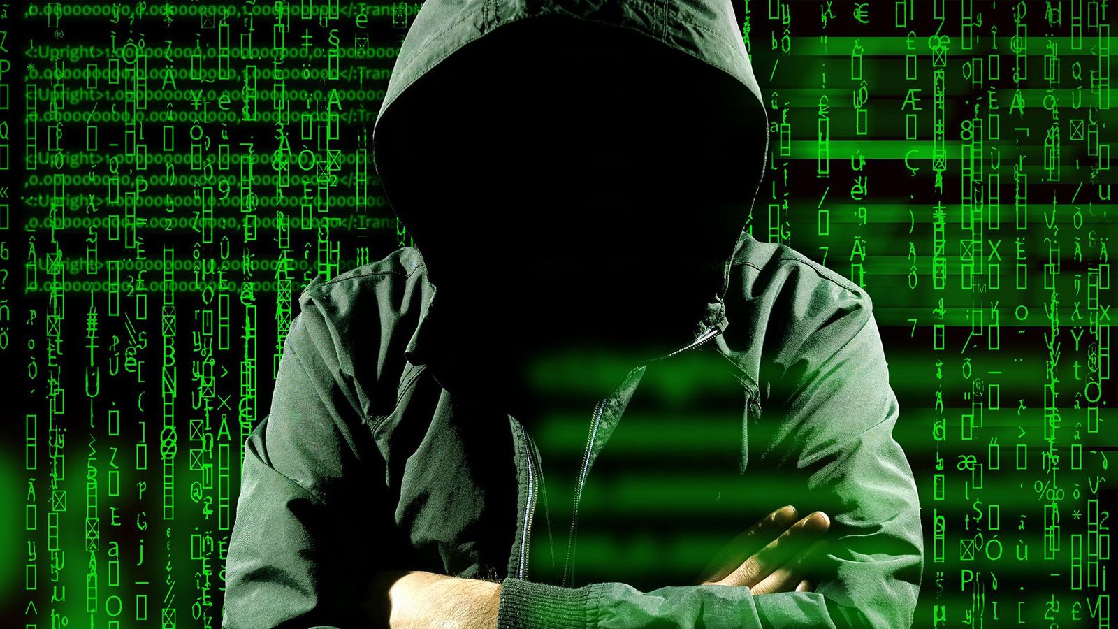 a dark figure in a hoodie with their arms crossed surrounded by various code-like green symbols on a dark background