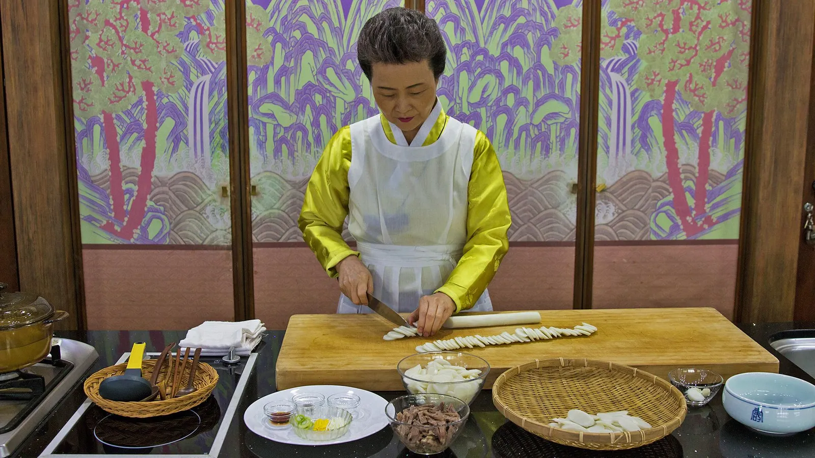 Dr Sook-ja Yoon in traditional Korean dress, Hanbok, preparing Tteokguk ingredients.