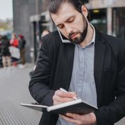Man on phone writing notes while walking thumbnail