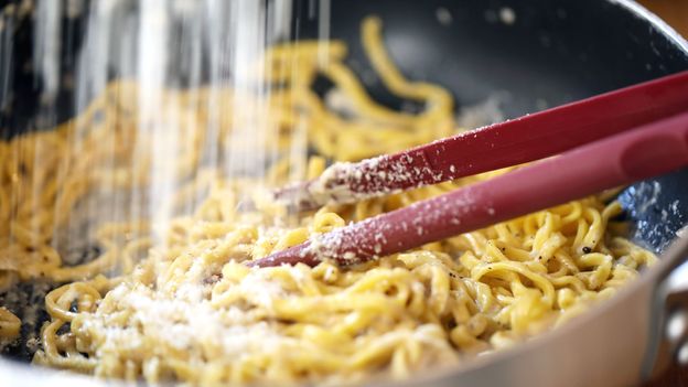 In making cacio e pepe, grated cheese is added to the pasta from above, while shaking the pan to coat evenly (Credit: Credit: Cavan Images/Getty Images)
