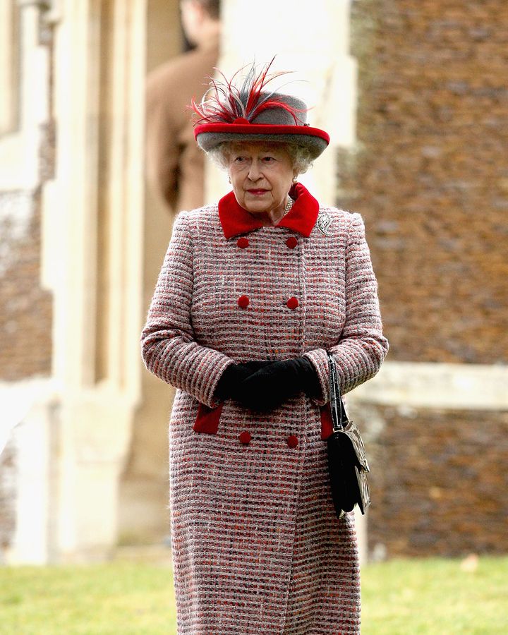 A classic tweed coat with a festive red trim was the outfit for a Christmas Day church service at Sandringham – the handbag is by Launer (Credit: Getty Images)