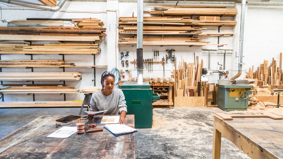 Young black female designer working in a woodworking workshop.