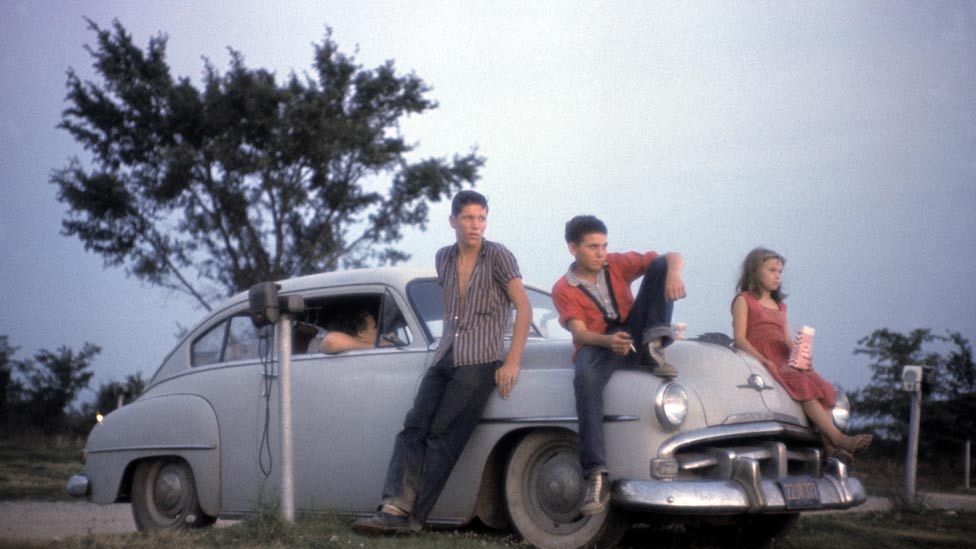Young people sit on the hood of a car in California in 1960. Drive-ins were an intoxicating, all-American mix of motoring and the movies. (Photo: Wayne Miller/Magnum Photos)
