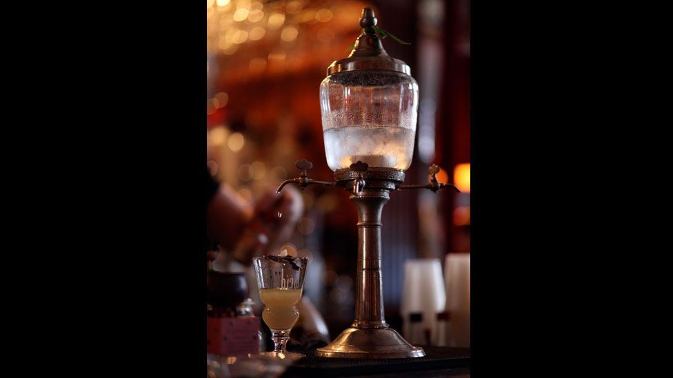 The drink was often prepared in a fountain – or poured over sugar cubes suspended above a cup on a spoon – to dilute its bitter taste. (Wikimedia Commons) The drink was often prepared in a fountain – or poured over sugar cubes suspended above a cup on a spoon – to dilute its bitter taste. (Wikimedia Commons)