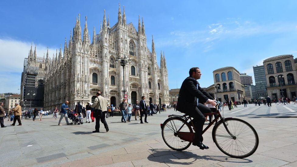 A cyclist rides through Milan's piazza del Duomo