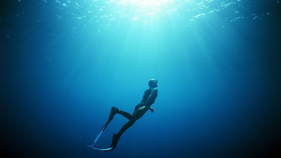 A freediver returns to the surface through rays of sunlight (Science Photo Library)