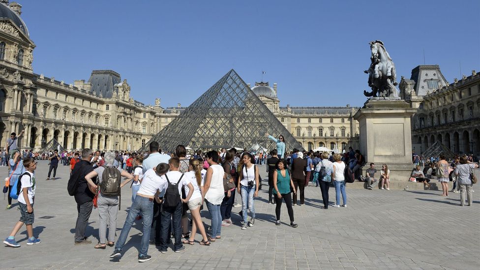 Visitors wait outside the Louvre's main entrance on a summer day. (Miguel Medina/AFP/Getty)