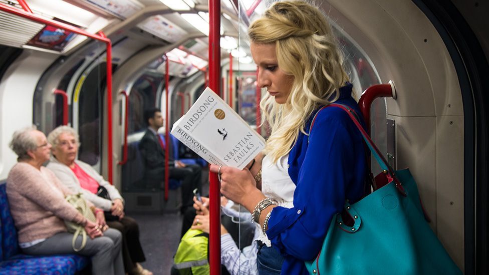 Она читает в метро. Блондинка в метро. Девушка блондинка в метро. Люди в наушниках в метро. Девушка читает в метро.