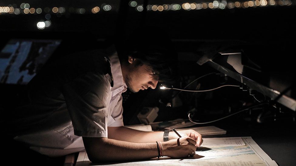 A crew member updates navigation charts (Kate Davies/Unknown Fields) A crew member updates navigation charts (Kate Davies/Unknown Fields)