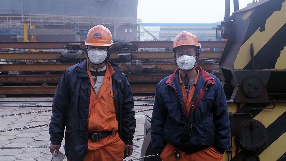 Two shipyard workers take a break from the fumes (Liam Young/Unknown Fields) Two shipyard workers take a break from the fumes (Liam Young/Unknown Fields)