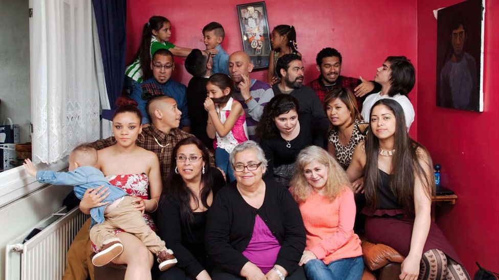 Ana Tordecilla, in a black dress (front), sits next to her mother Anita Rodriquez, surrounded by relatives. The family is from Chile. (Credit: Chris Steele-Perkins/Magnum Photos)