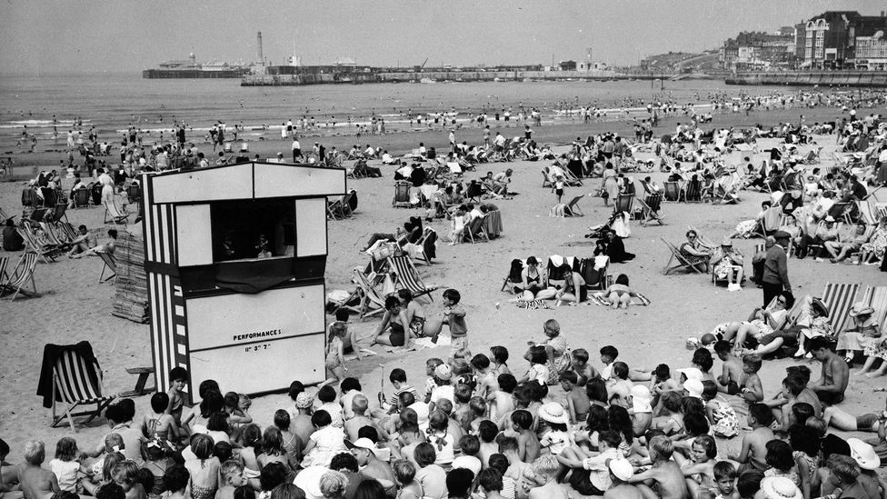 Crowds pack the beach on a summer day in Margate in 1961. In the foreground, children gather to watch a Punch and Judy show. (Credit: George W Hales/Getty Images)