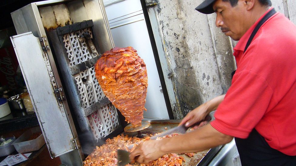 The pork is marinated, roasted by an open flame and carved off (Credit: Kent Wang/Torta Brava/Flickr/CC BY-SA 2.0) The pork is marinated, roasted by an open flame and carved off (Credit: Kent Wang/Torta Brava/Flickr/CC BY-SA 2.0)