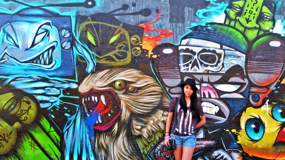 Adalid poses in front of graffiti art in her home country, the Philippines (Credit: Aileen Adalid) Adalid poses in front of graffiti art in her home country, the Philippines (Credit: Aileen Adalid)