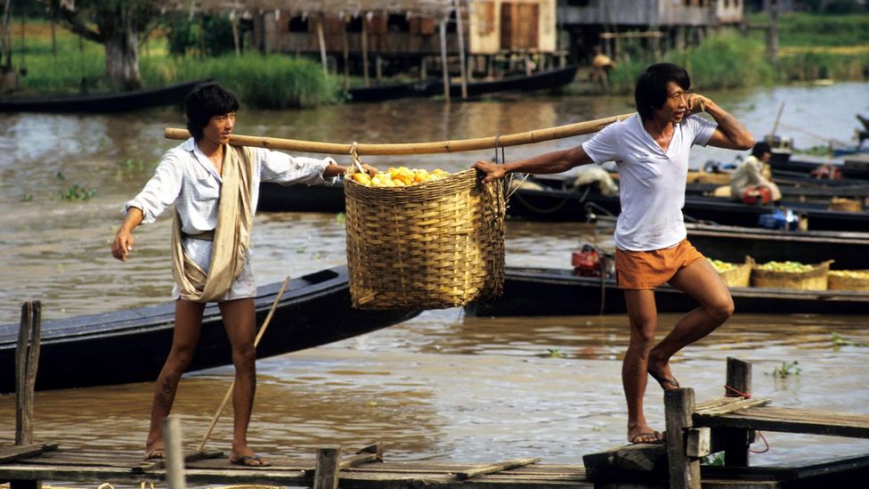 Market workers disembark from a boat carrying baskets full of tomatoes on Inle Lake (Credit: incamerastock/Alamy)