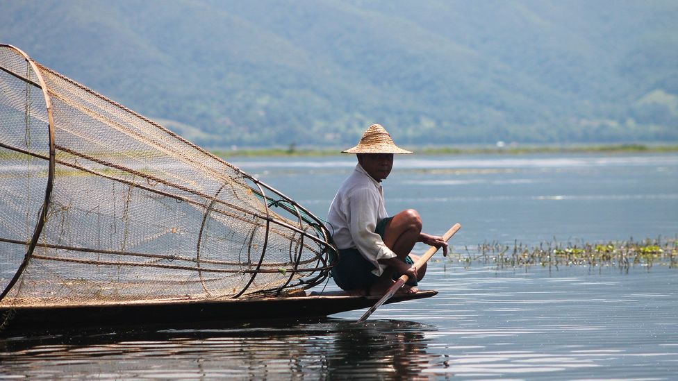 A rower rests his legs on the tranquil Inle Lake (Credit: Adrienne Jordan)