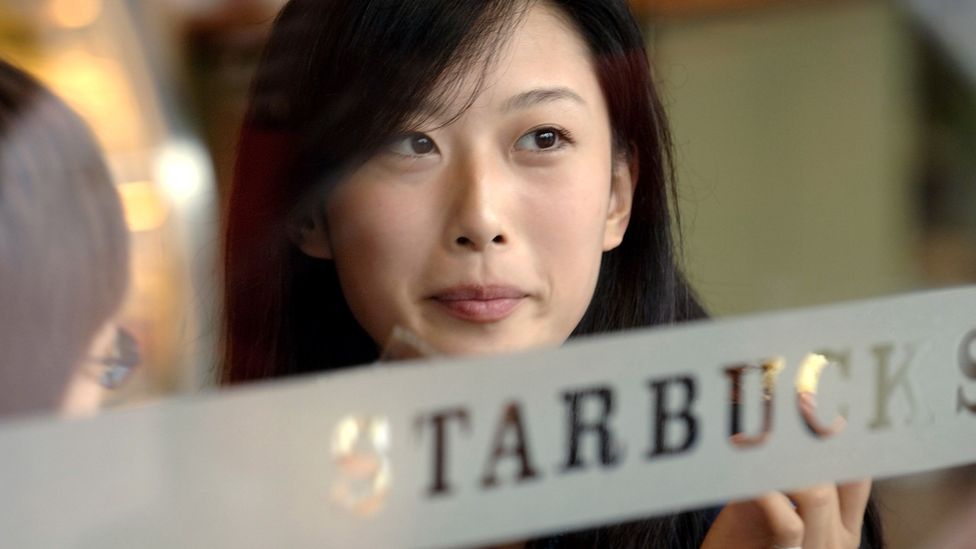 Wang Yili, fashion model in Beijing, has coffee at local Starbucks, Xidan District. Foreign companies and cultures have made huge inroads. (Credit: Joe McNally/Getty Images)