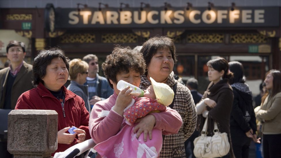 Woman feeds baby outside Starbucks in the Yu Garden Bazaar, China (Credit: Tim Graham/Getty Images)