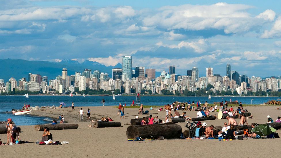 People relax on a beach with a view of the downtown Vancouver skyline (Credit: David Pearson/Alamy)