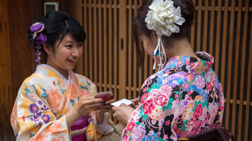 Women wearing traditional kimono costume swap cards in Kyoto, Tokyo, Japan (Credit: Getty Images)