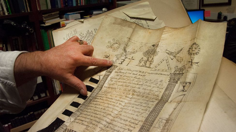 Cooper points to the Masonic symbols on one of the many historic documents in the lodge’s archive (Credit: Amanda Ruggeri) Cooper points to the Masonic symbols on one of the many historic documents in the lodge’s archive (Credit: Amanda Ruggeri)