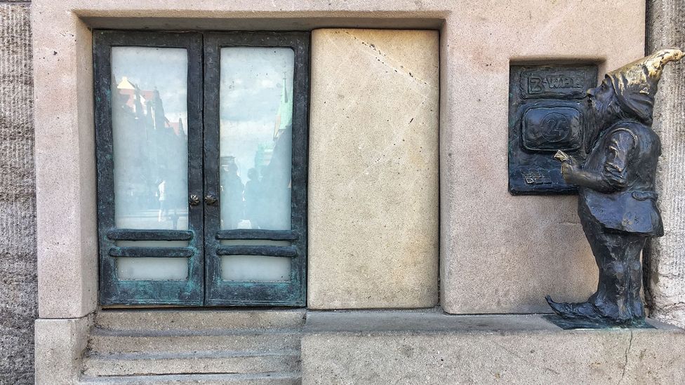 A tiny bronze dwarf withdraws money at the ATM steps away from a bank in Wrocław’s Market Square (Credit: Eliot Stein)