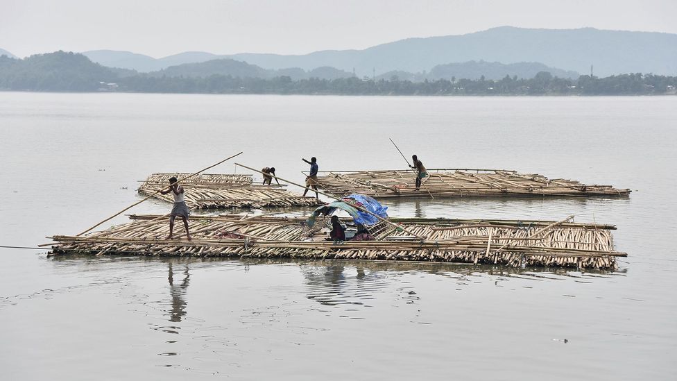 The sapori people paddle rafts on the Brahmaputra River in South Kamrup, India (Credit: Getty Images)