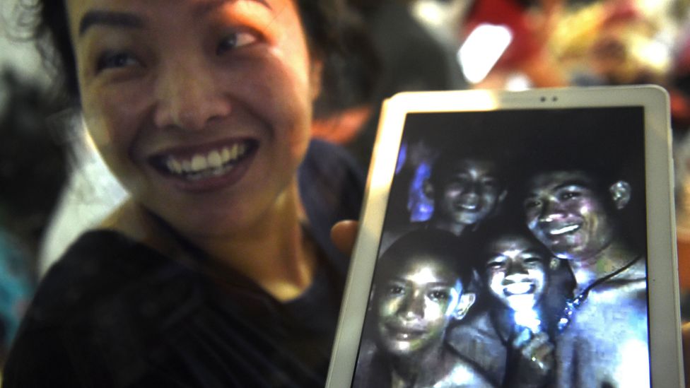 A family member shows a picture believed to have been taken in 2017 of four of the 12 missing boys (Credit: Lillian Suwanrumpha/AFP/Getty Images)