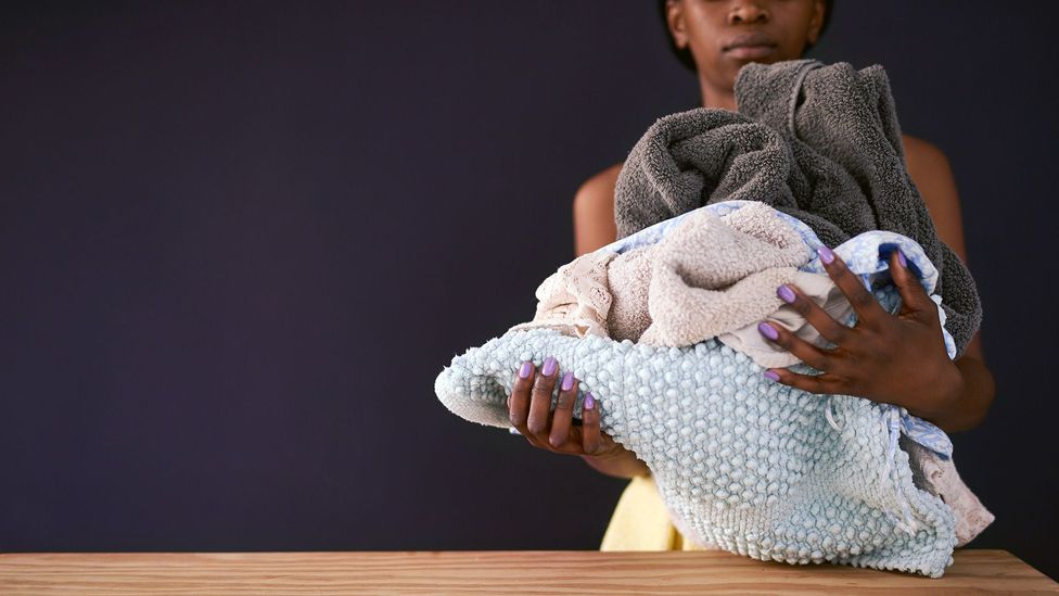 A woman is shown holding a pile of laundry (Credit: Getty Images)