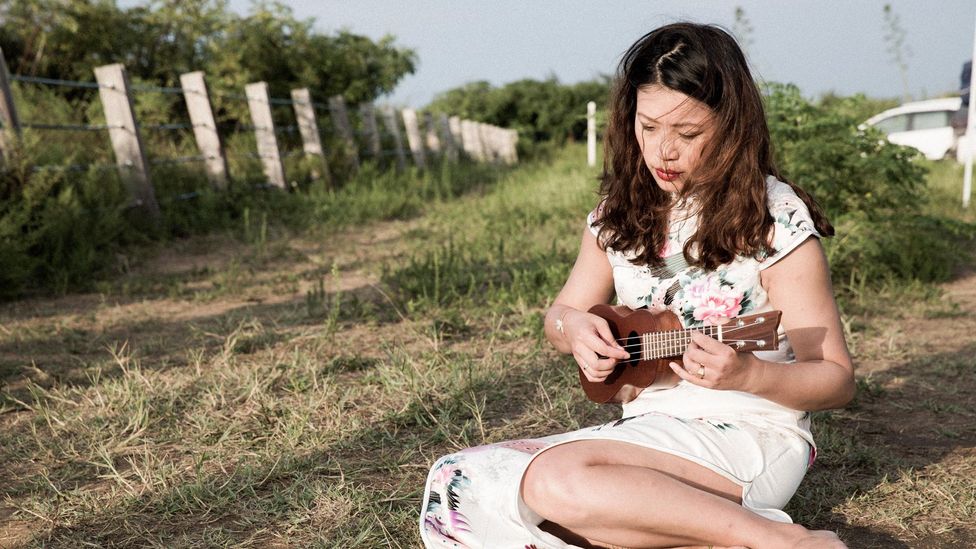 Chang performs songs that were played to soldiers in the past, moving from inside the tower to sit on the grass outside (Credit: Shao Po Chao) Chang performs songs that were played to soldiers in the past, moving from inside the tower to sit on the grass outside (Credit: Shao Po Chao)