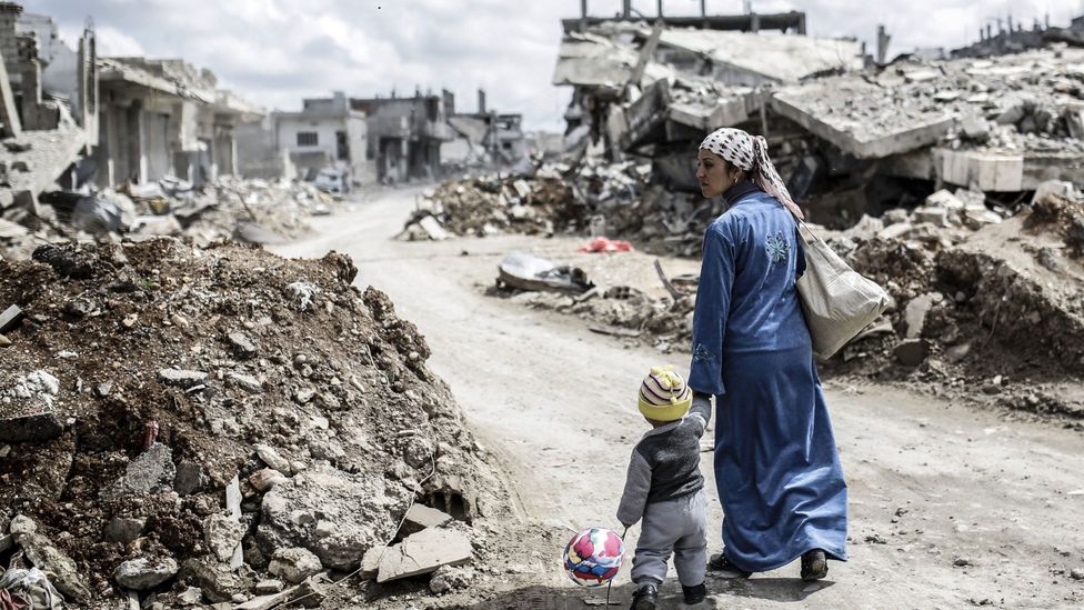 A woman walks in the ruins of a town in Syria following conflict between fighters (Credit: Getty Images) A woman walks in the ruins of a town in Syria following conflict between fighters (Credit: Getty Images)