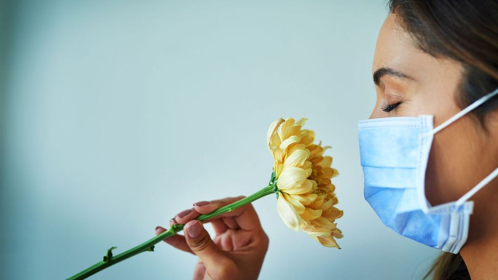Woman in mask snigging flower (Credit: Getty Images)