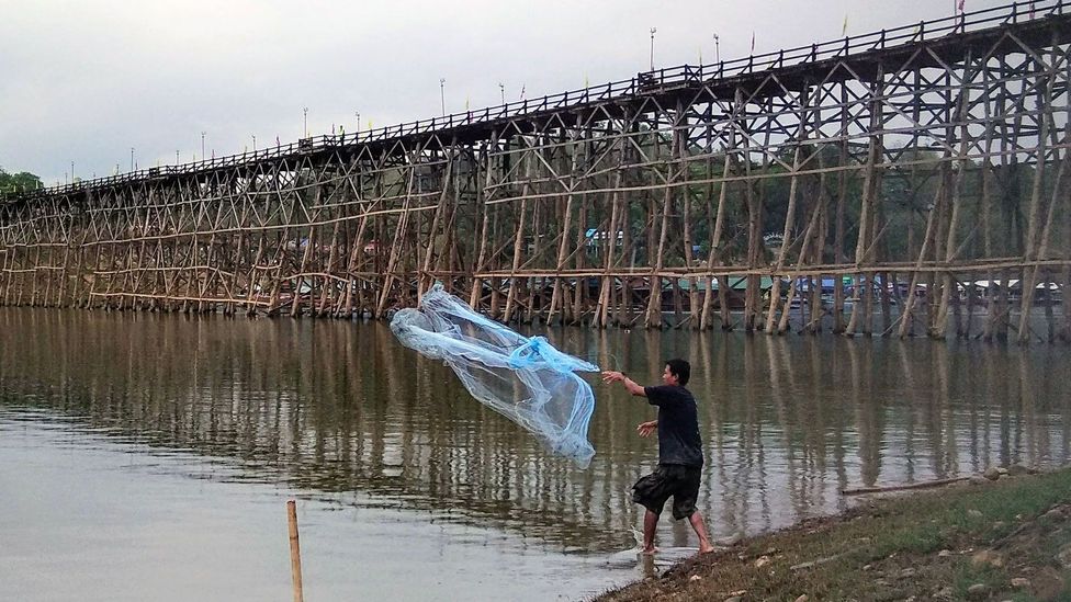 A man fishes near the Mon Bridge in Sangkhlaburi, Thailand A man fishes near the Mon Bridge in Sangkhlaburi, Thailand