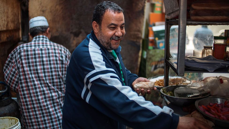 Amir, who operates a food cart in Cairo, Egypt, smiles beneath his greying mustache as he prepares taameya (Credit: Hamada Elrasam)