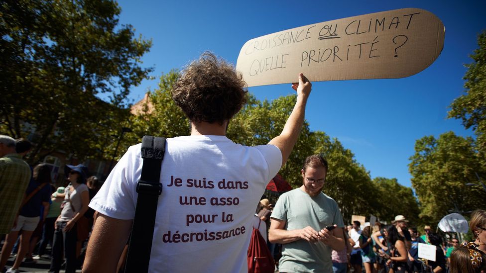 A degrowth protester in France in 2018 holds a placard that reads, "grow or climate, which priority"? (Credit: Getty Images) A degrowth protester in France in 2018 holds a placard that reads, "grow or climate, which priority"? (Credit: Getty Images)