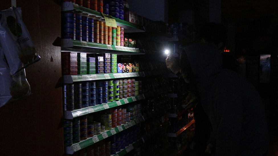 People use phones to illuminate goods in a supermarket in Buenos Aires, Argentina during a power cut (Credit: Getty Images)