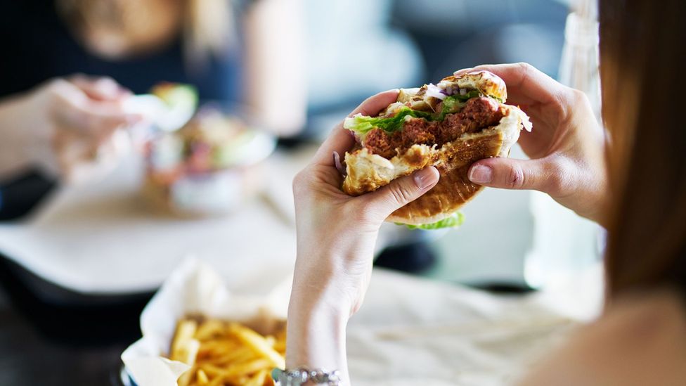 Woman eating vegan burger (Credit: Getty Images)