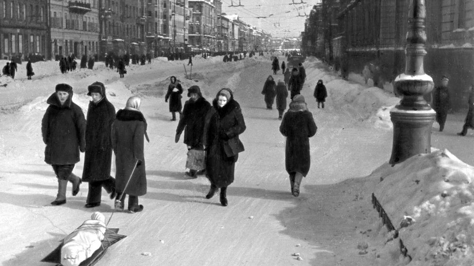 Residents walk through the streets of besieged Leningrad. One pulls the body of a dead relative on a sled (Credit: Getty Images)