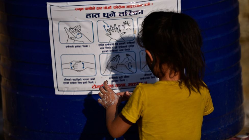 A young girl follows a poster on hand washing (Credit: Getty Images)