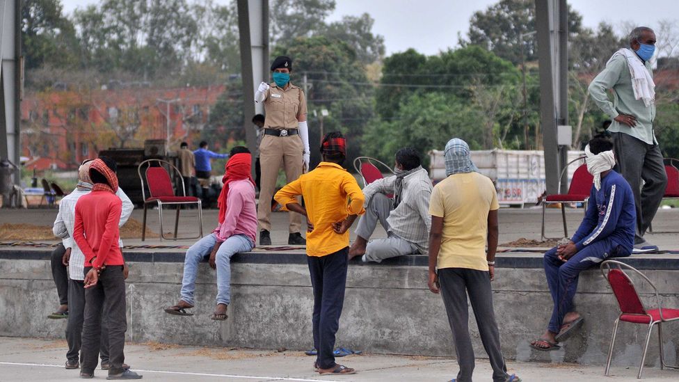 A police official warns labourers to wear face masks at the grain market in Chandigarh, India (Credit: Getty Images)