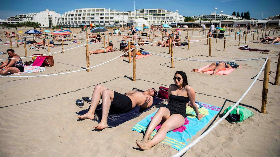 People sunbathe in a roped-off distancing zone at a beach in southern France (Credit: Getty Images)