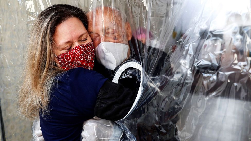 A woman hugs her 82-year-old father through a "hug curtain", in Sao Paulo, Brazil, one of the worst affected regions in the world (Credit: EPA)