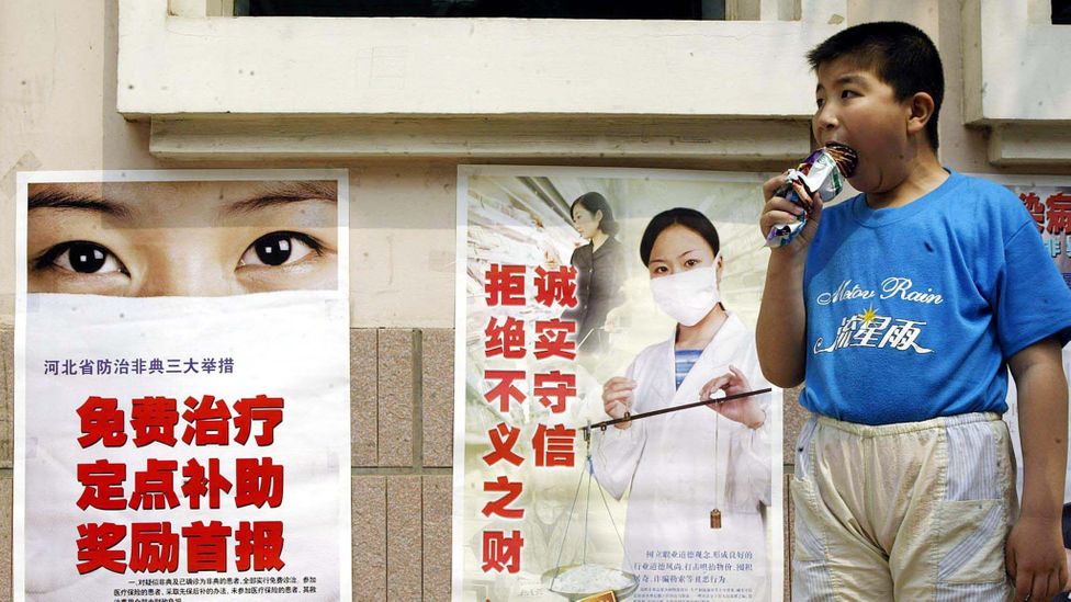 In front of posters about the Sars epidemic, a boy eats ice cream, which we collectively spend more on than preventing extinction through our technology (Credit: Getty Images)