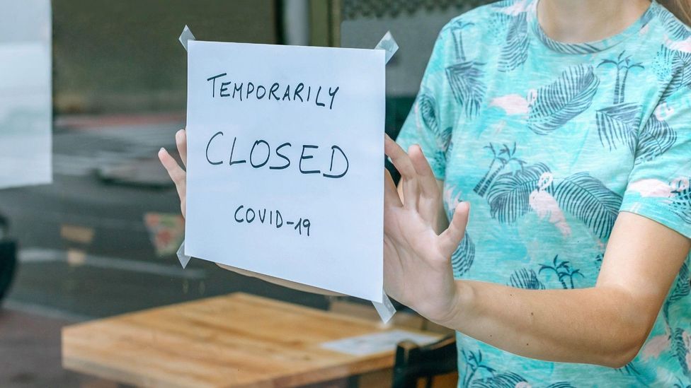 File image of woman placing a &#39;Closed&#39; sign on a cafe