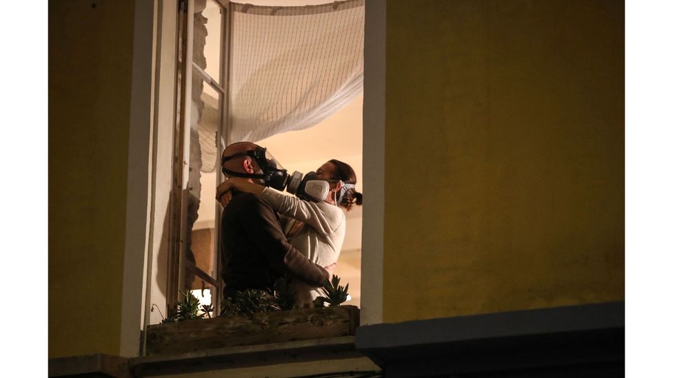 A couple wearing masks embrace during a daily round of applause for health workers in Nice, March 2020 (Credit: Valery Hache/AFP via Getty Images)