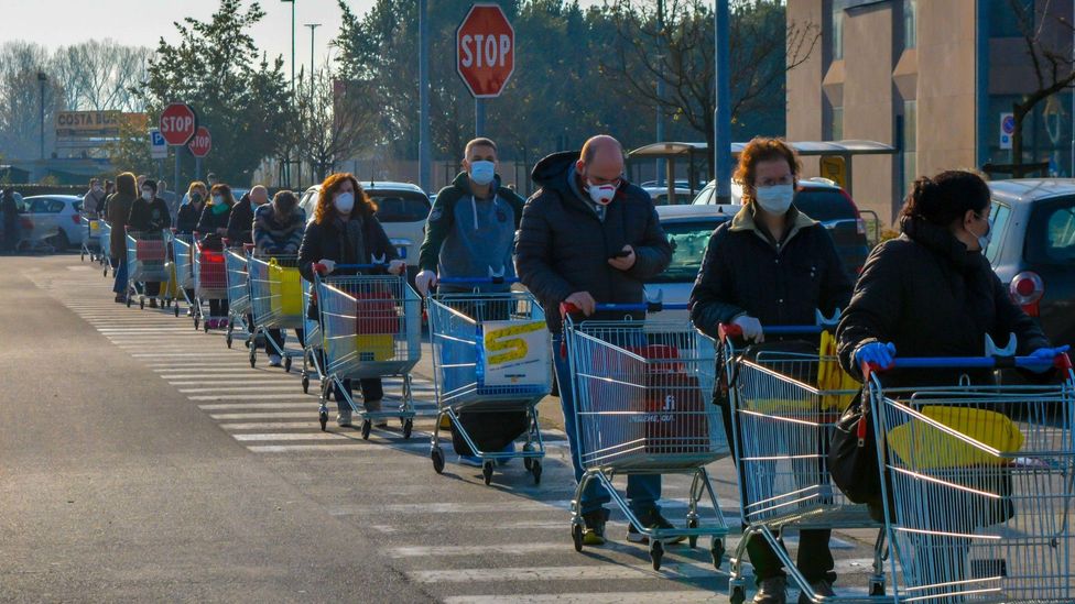 File image of masked shoppers queueing to enter a supermarket