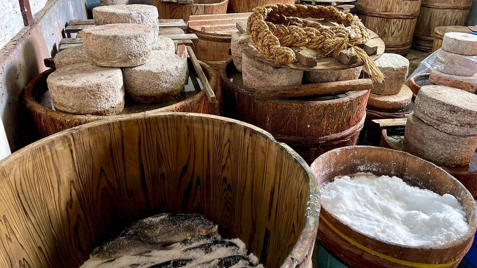 In Kitashina's storeroom, 30kg stones weigh down wooden tubs packed with salted, curing fish (Credit: Tom Schiller)