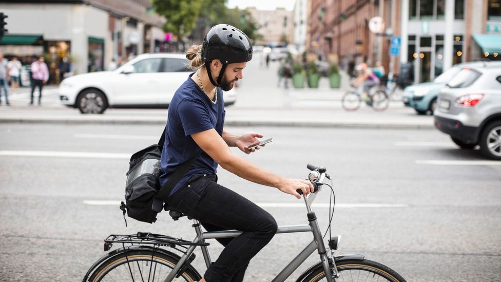 Man checks his phone while riding a bike